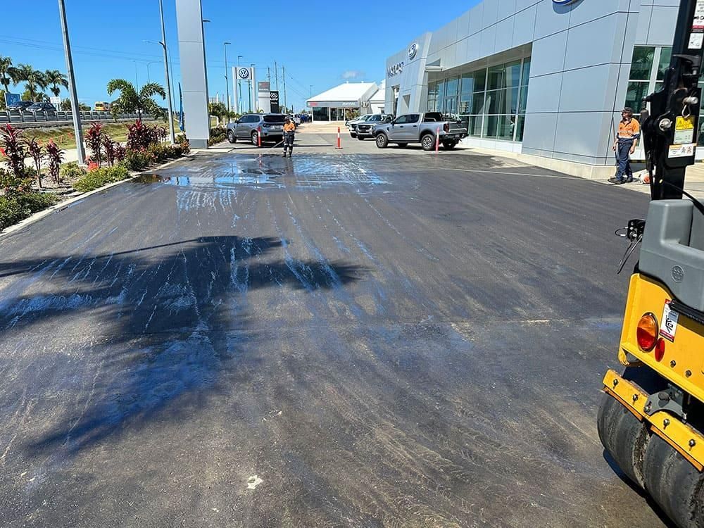 A Road Is Being Paved In Front Of A Car Dealership — Elite Bitumen & Asphalt In Mackay, QLD