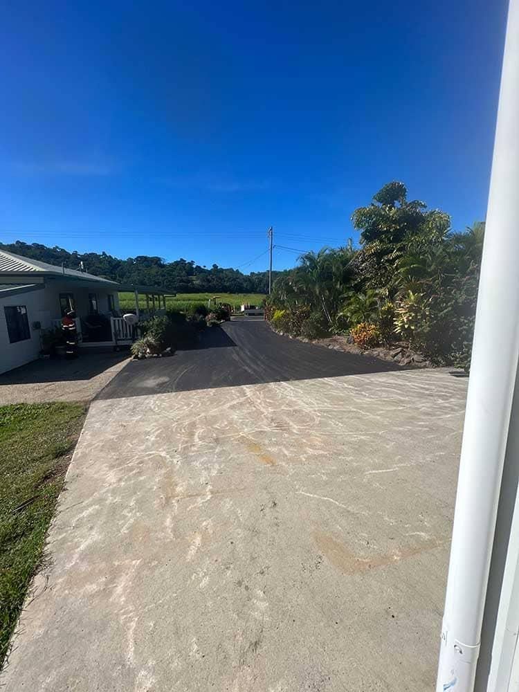 A Concrete Driveway Leading To A House On A Sunny Day — Elite Bitumen & Asphalt In Mackay, QLD