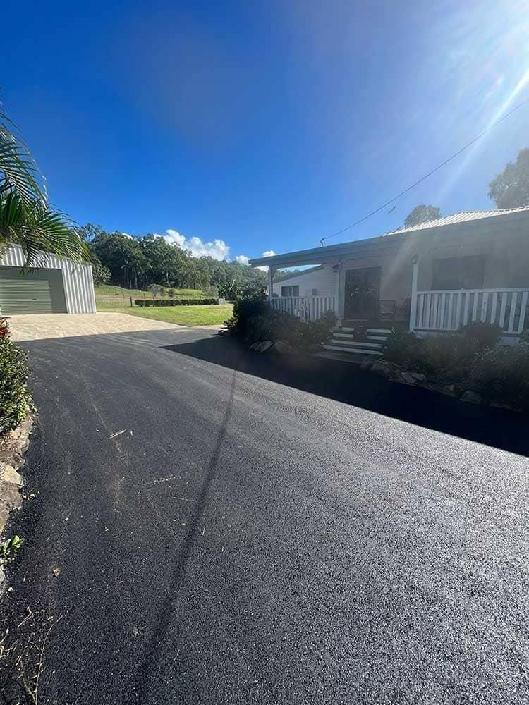A House Is Sitting On The Side Of A Road Next To A Driveway — Elite Bitumen & Asphalt In Mackay, QLD