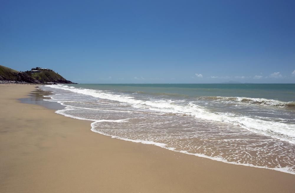 A Sandy Beach With Waves Crashing Against The Shore On A Sunny Day — Elite Bitumen & Asphalt In Sarina, QLD
