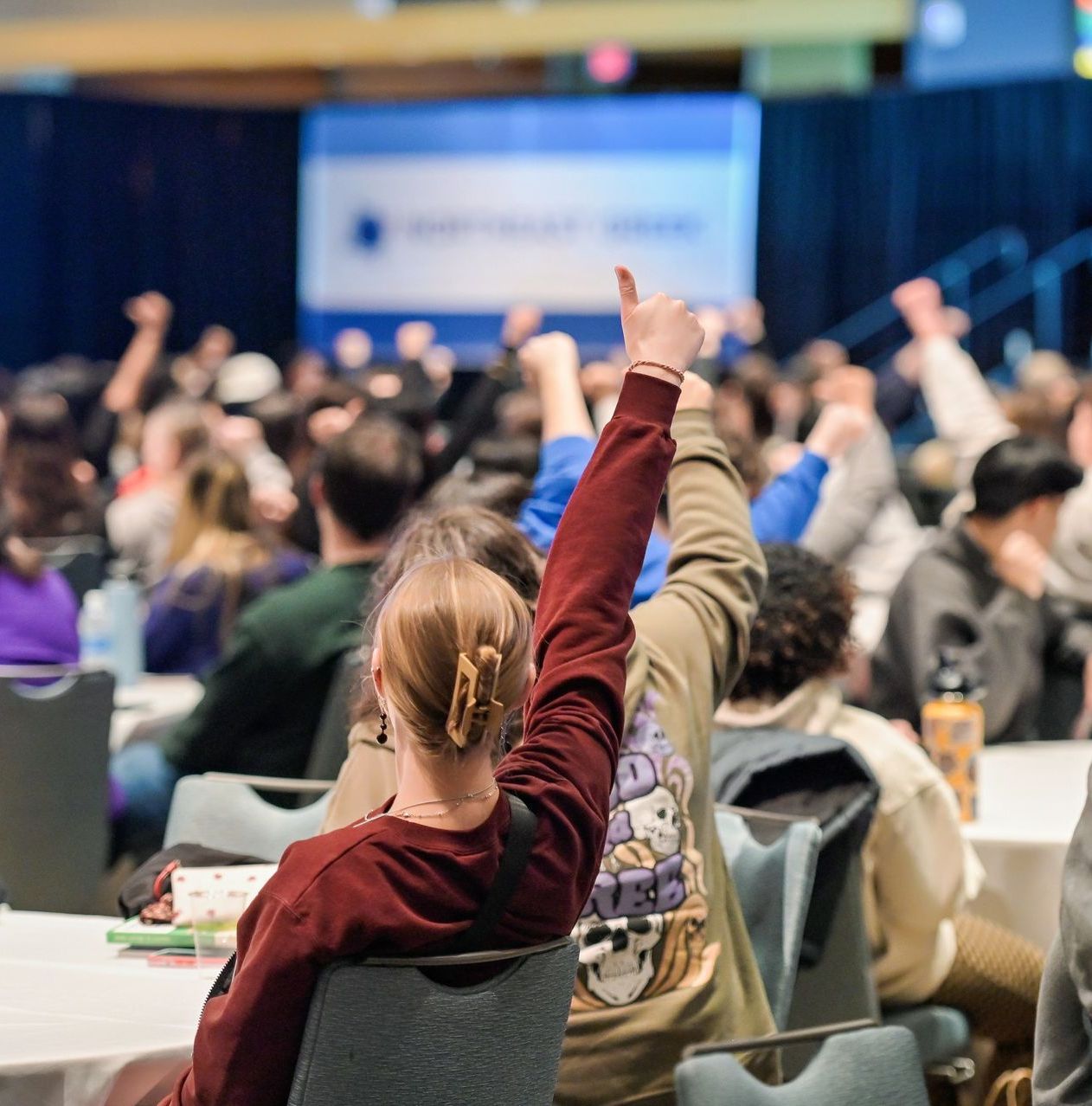 Conference attendees holding their thumbs up.