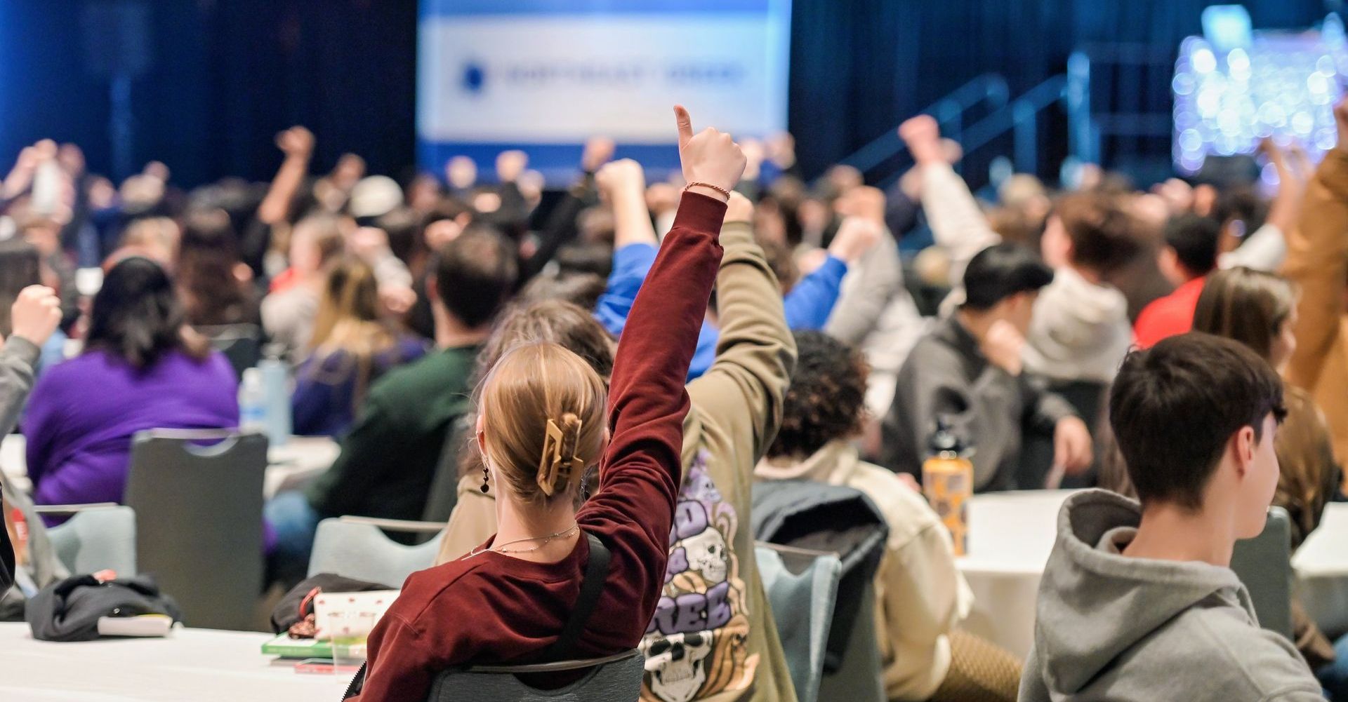 Conference attendees holding their thumbs up.