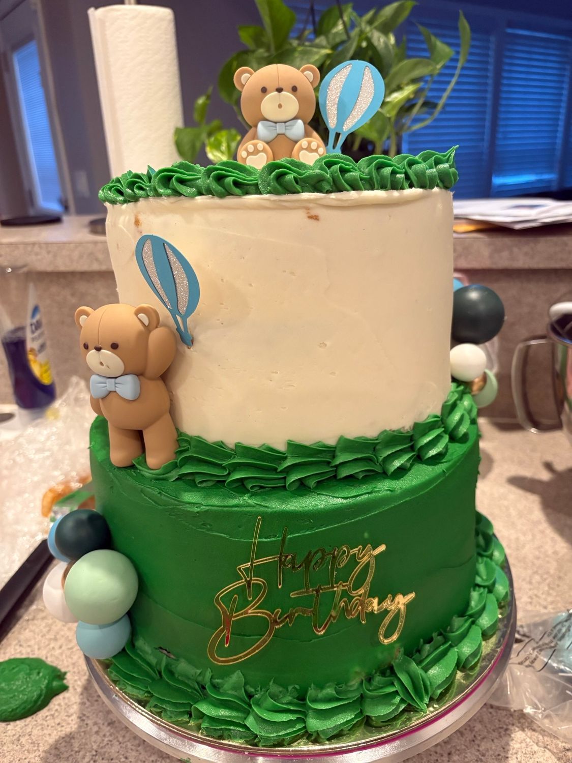 Green and white teddy bear cake with hot air balloons on a table
