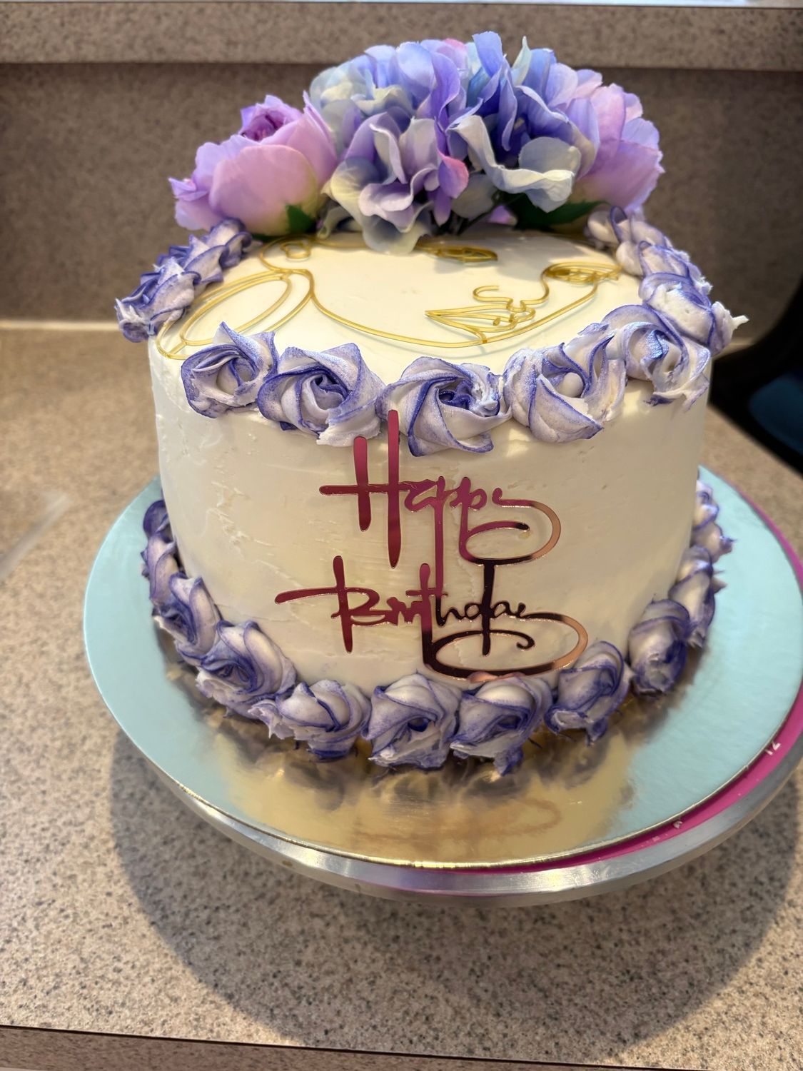 Lavender and white decorated birthday cake with flowers and red script on a silver cake stand