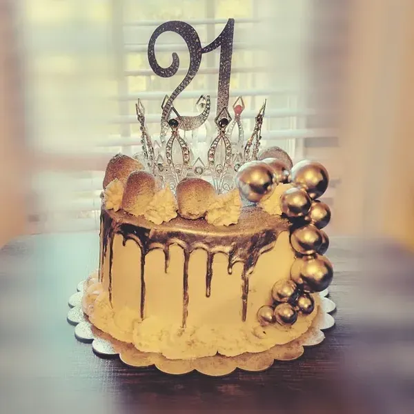 Gold drip cake with crown topper, gold balls, and a black “21” on top