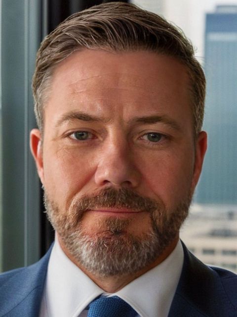 A man with a beard is wearing a suit and tie.
