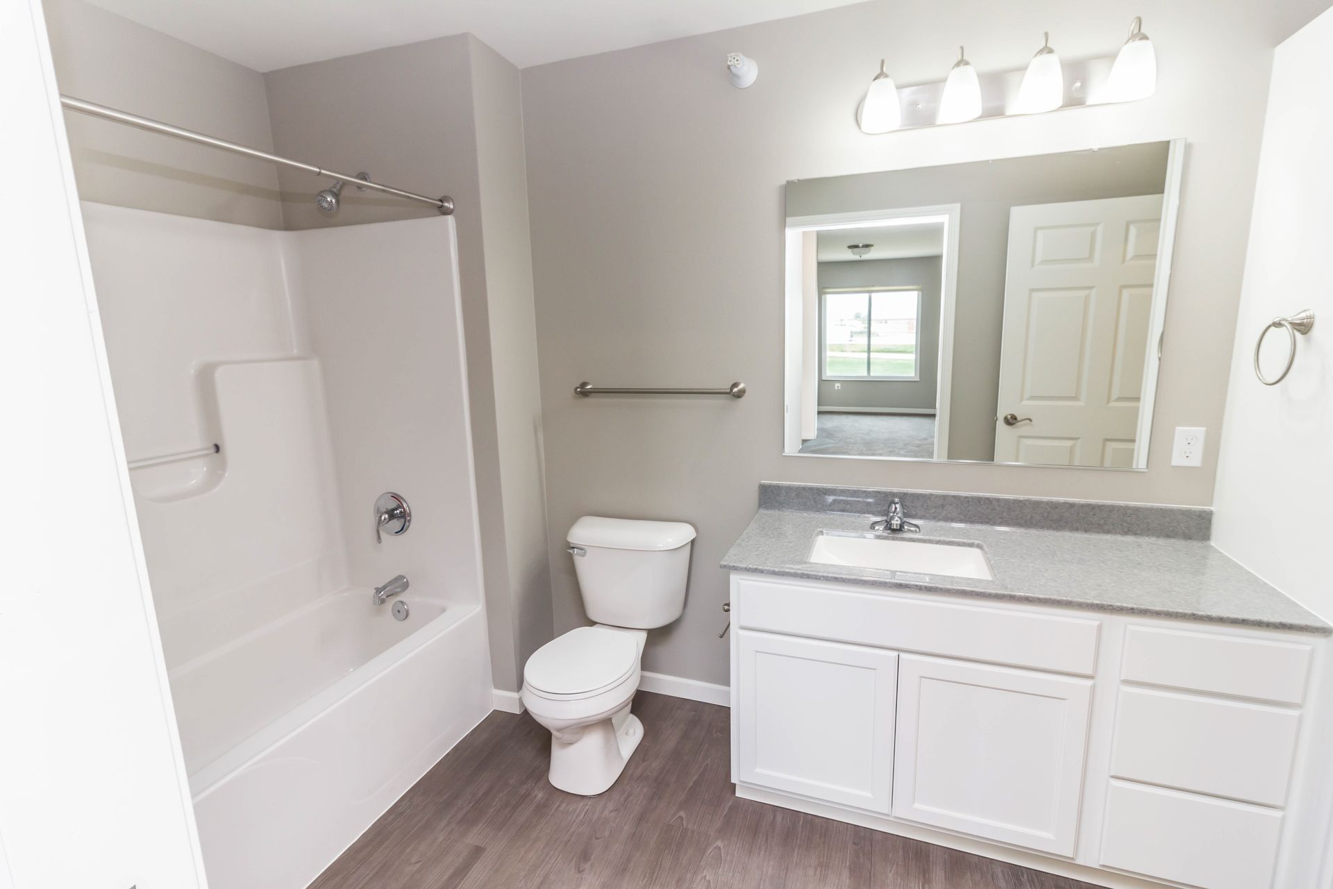 Bathroom with gray walls, white vanity and toilet, and a bathtub/shower combination.