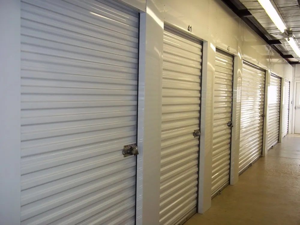 Rows of white storage unit doors in a brightly lit hallway.