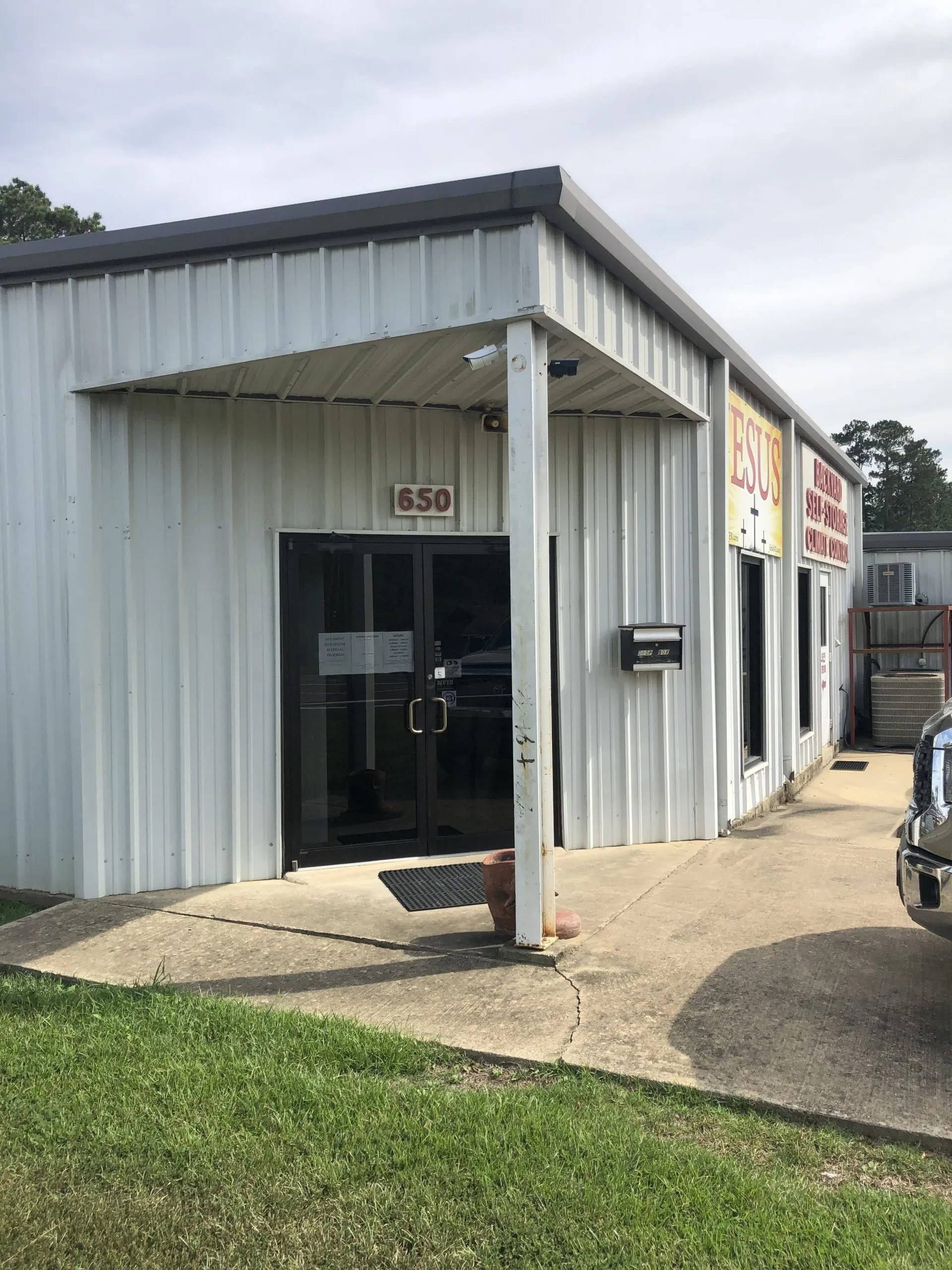 White commercial building with glass door, address 1450, and signs.