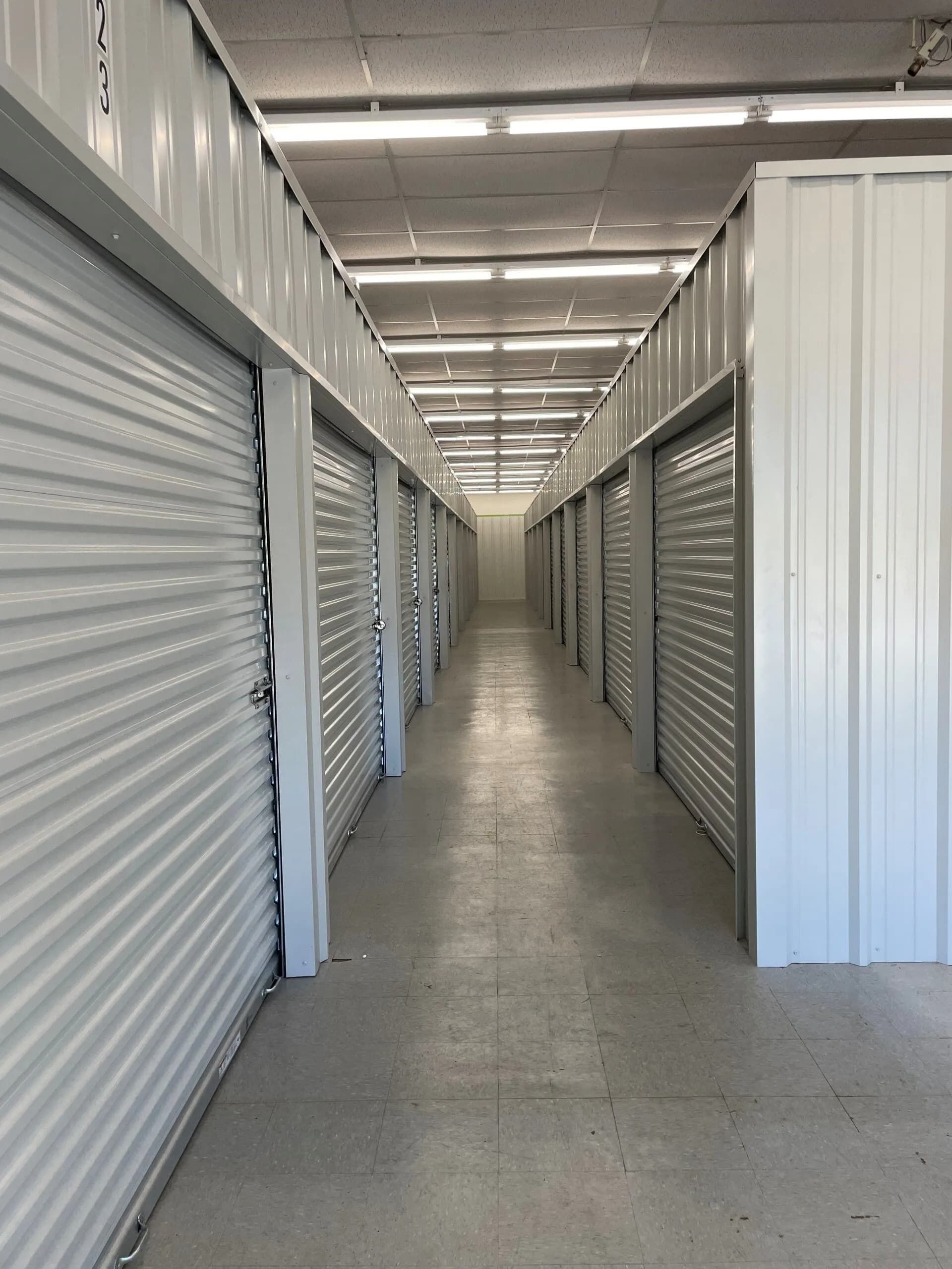 Interior of a storage facility hallway with numerous closed storage unit doors. 