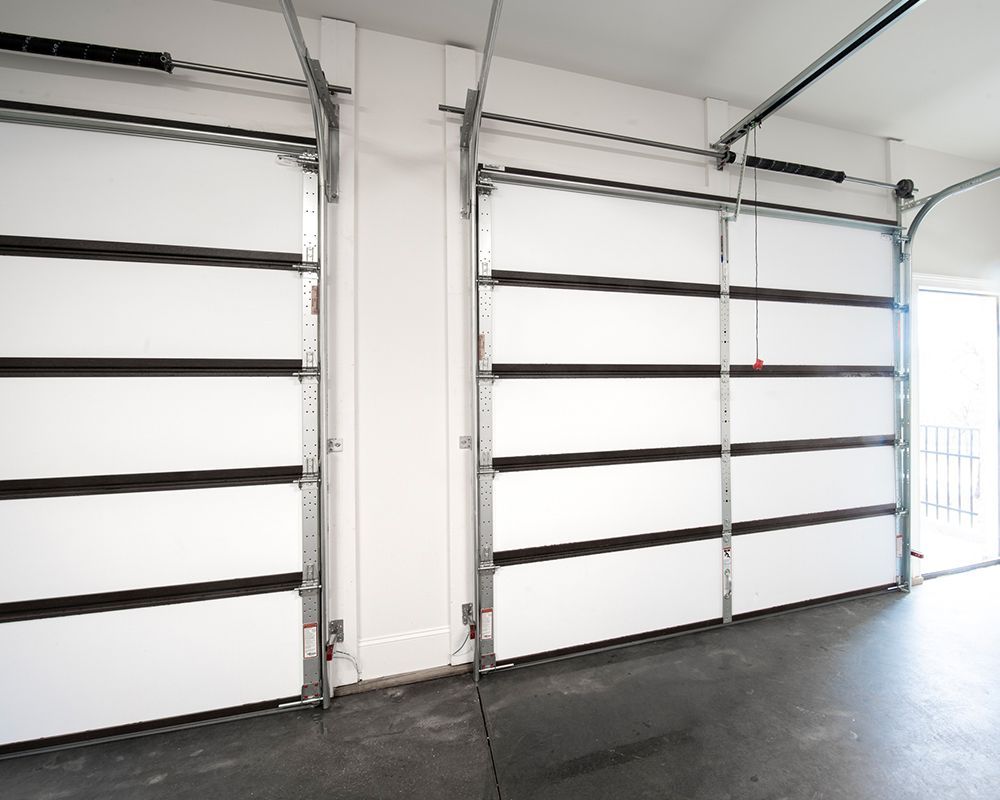 A garage with two white garage doors and a black floor.