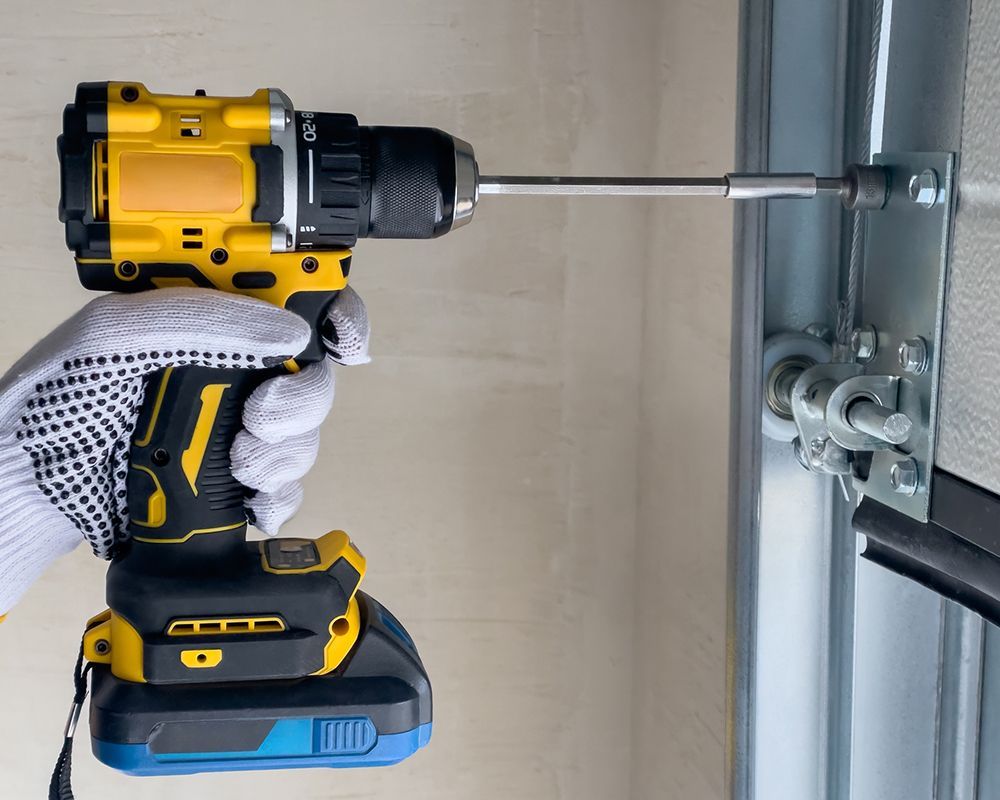 A worker using drill to repair garage door hinges