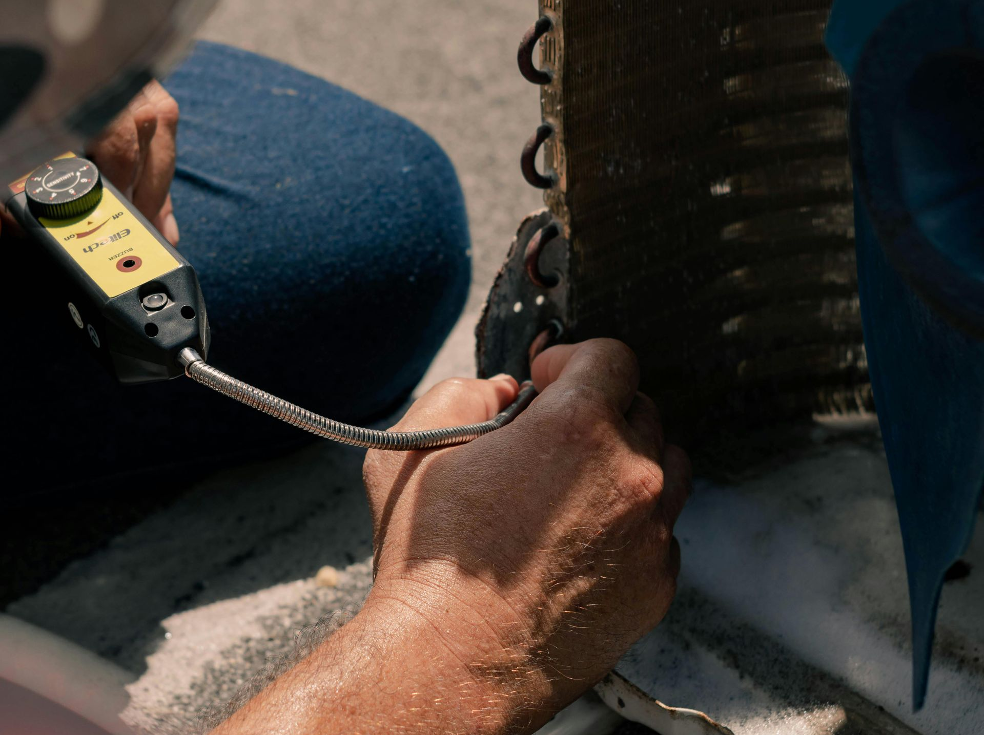 Person using a tool to inspect a metal component; hands close up.