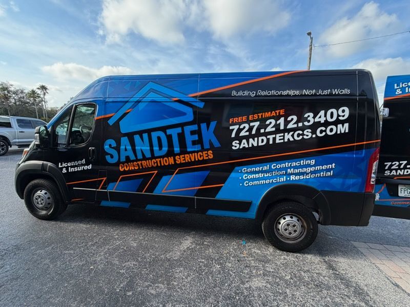 Black and blue Sandtek Construction Services van parked outdoors.
