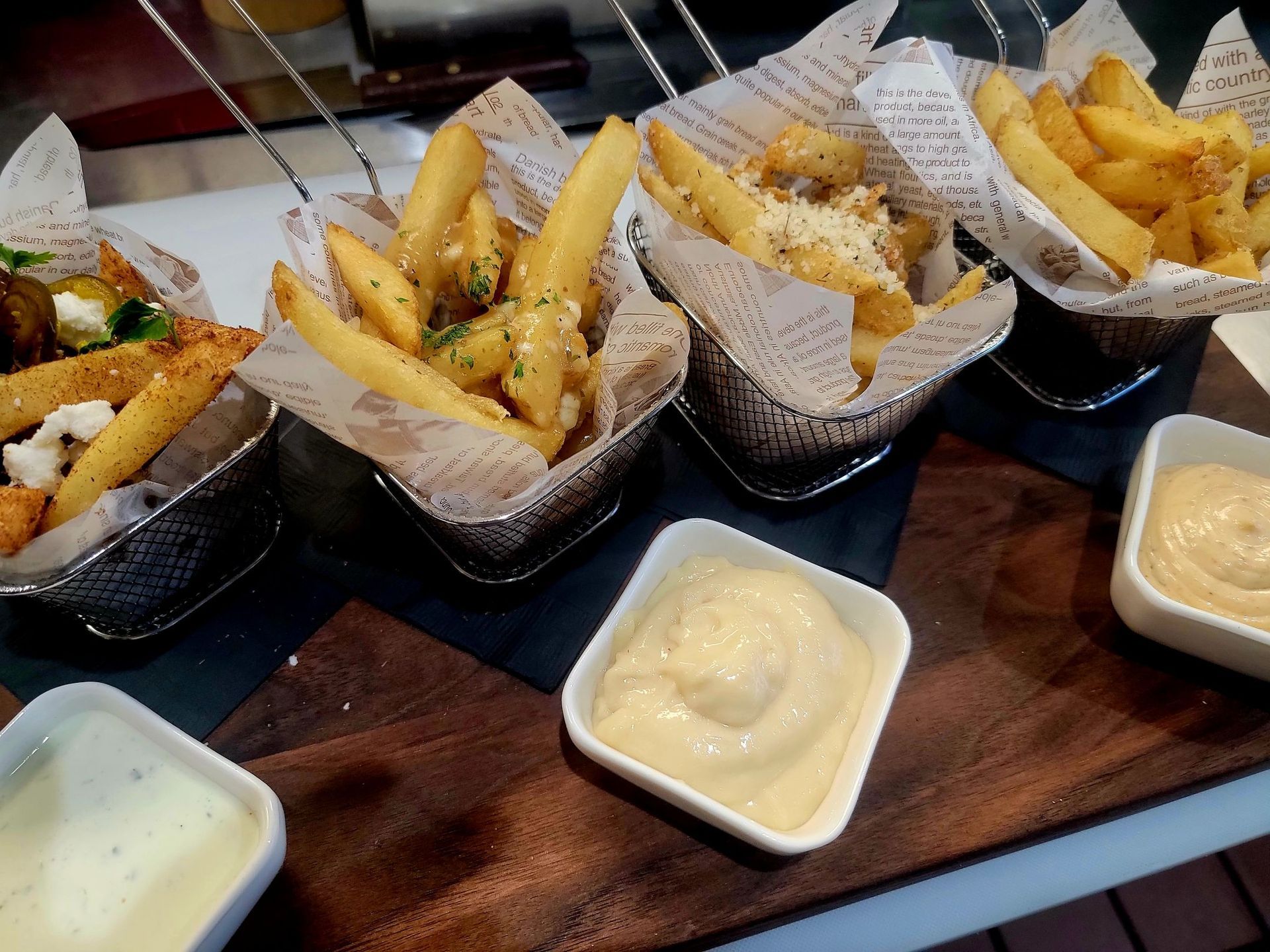 four types of different french fries served with various sauces