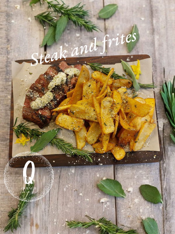 Steak and fries on a wooden board, garnished with herbs.