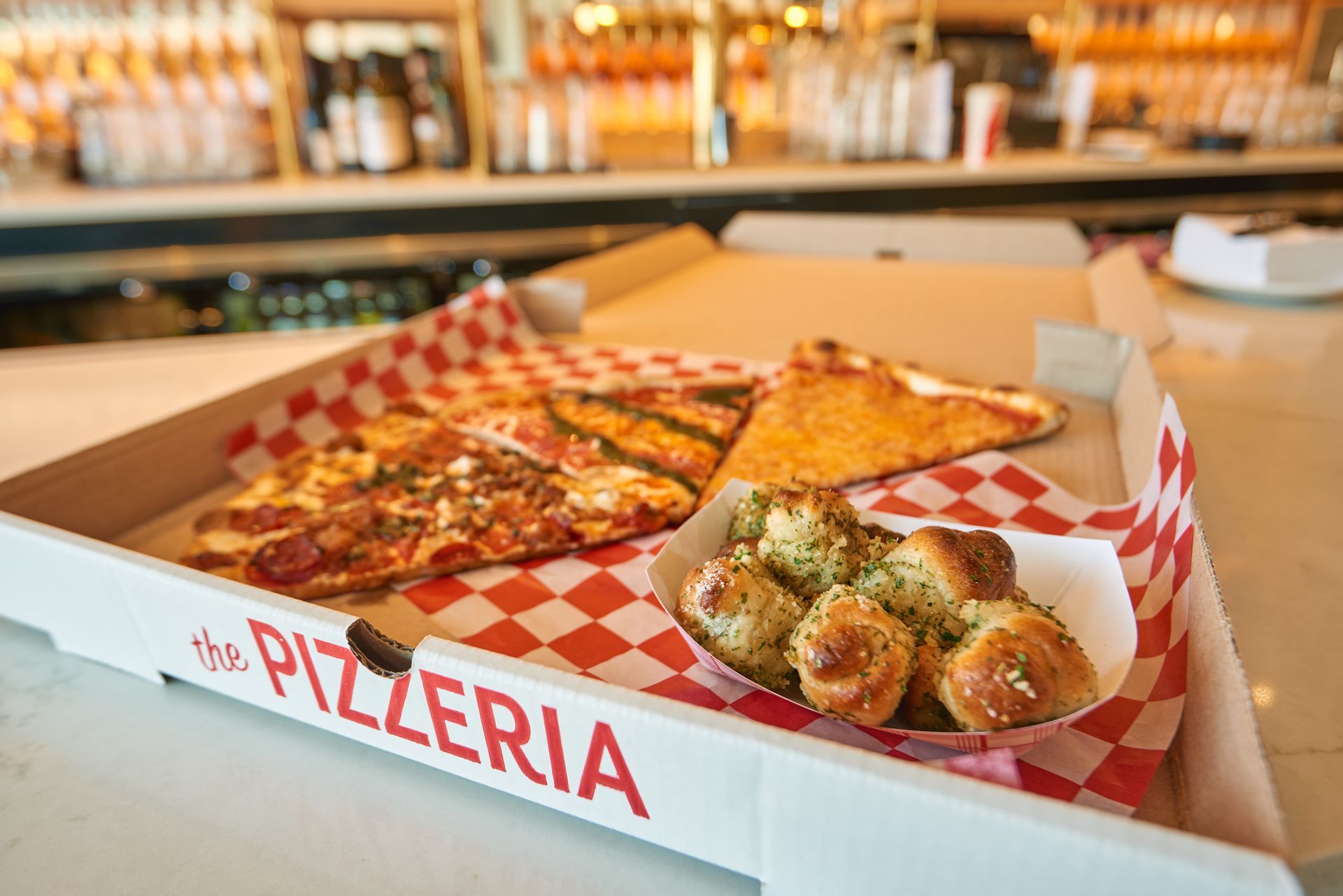 A pizza box filled with pizza and pretzels on a table.