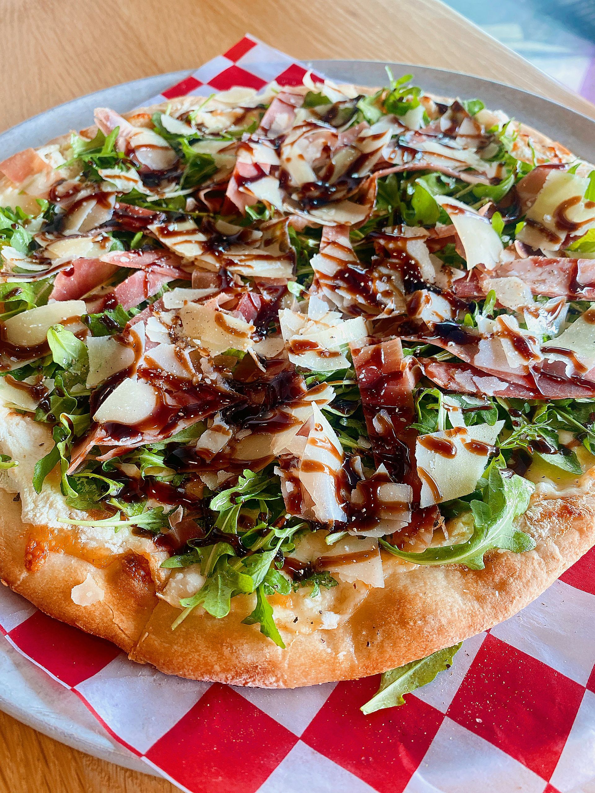 A pizza is sitting on a checkered napkin on a plate.