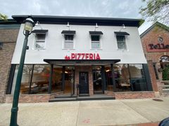 A white building with a red sign that says pizzeria