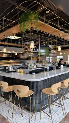 A bar with stools and a man standing behind it in a restaurant.