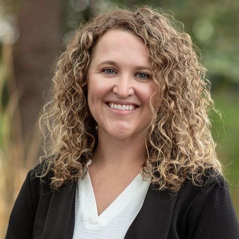 A woman with curly hair is smiling for the camera.