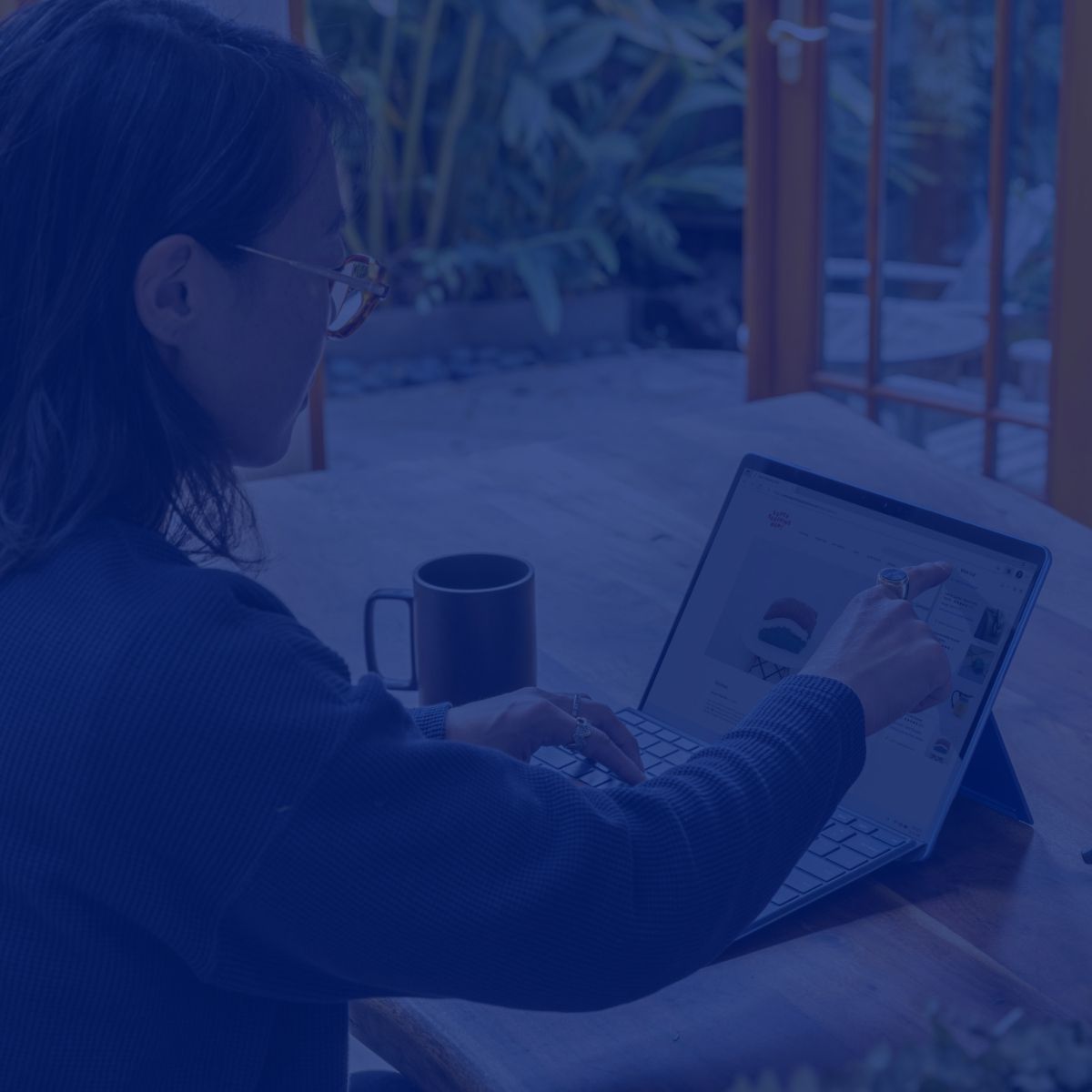 A woman is sitting at a table using a laptop computer.