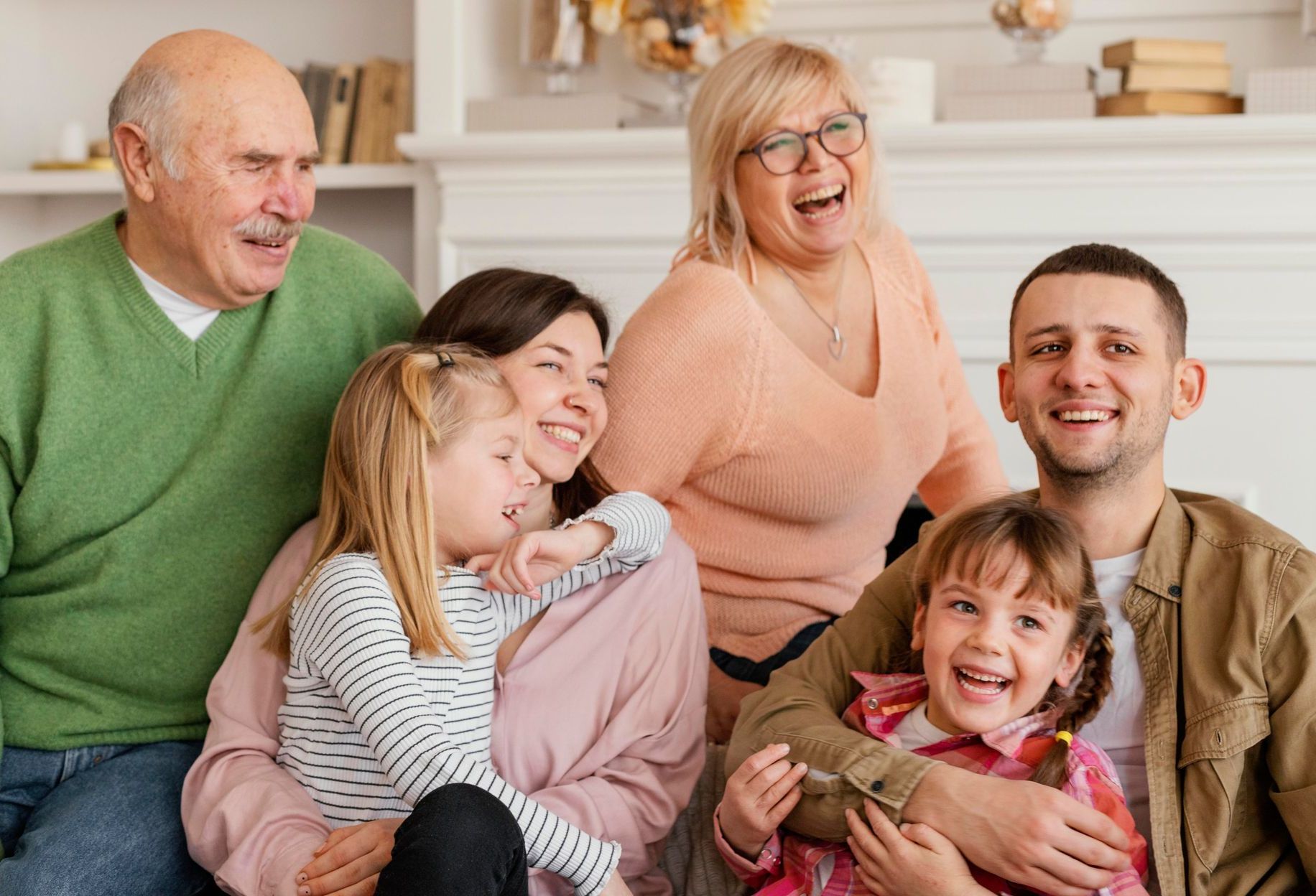 A large family is sitting on the floor in a living room.