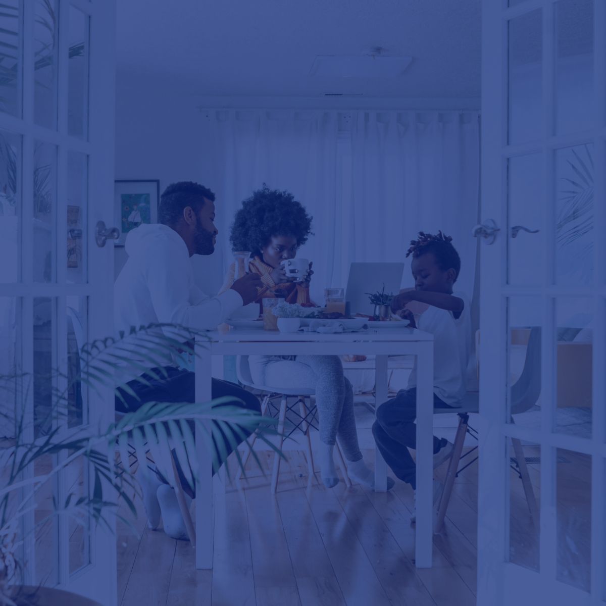A family is sitting at a table with a laptop.