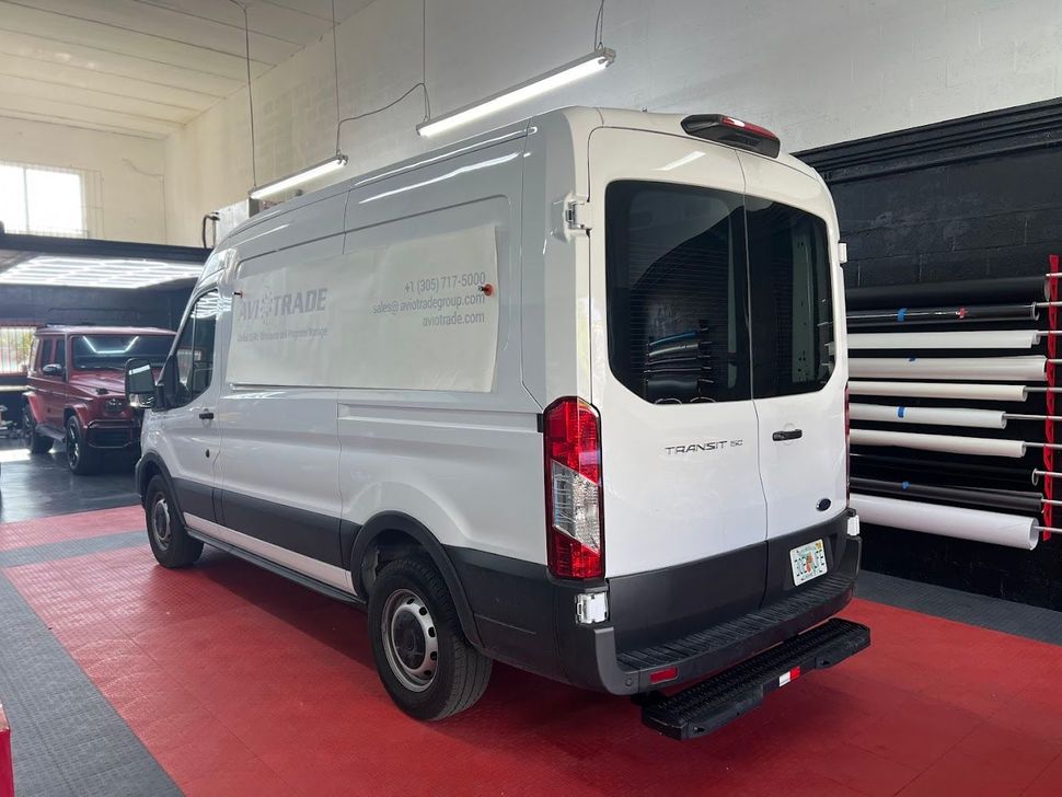 A white van is parked in a garage with a red floor.