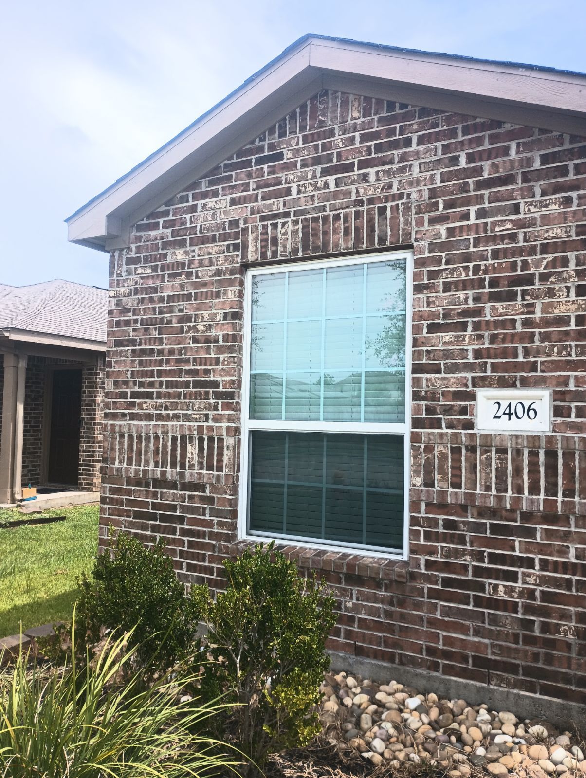 A person uses a screwdriver to adjust the white handle of a window frame.