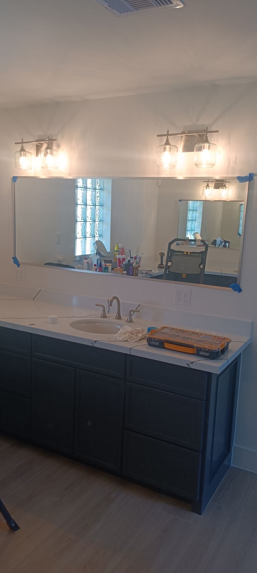 A modern bathroom with two oval mirrors above a beige stone double vanity, gold faucets, and simple decorative items.