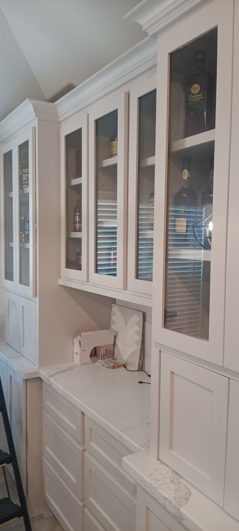A spacious bedroom with a large, white-framed wall unit featuring frosted glass doors, light wood floors, and mauve walls.