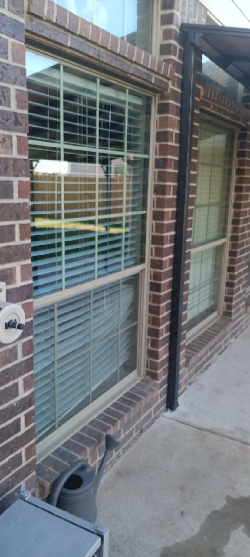 A construction worker in a white hard hat measures the side of a window frame with a tape measure.