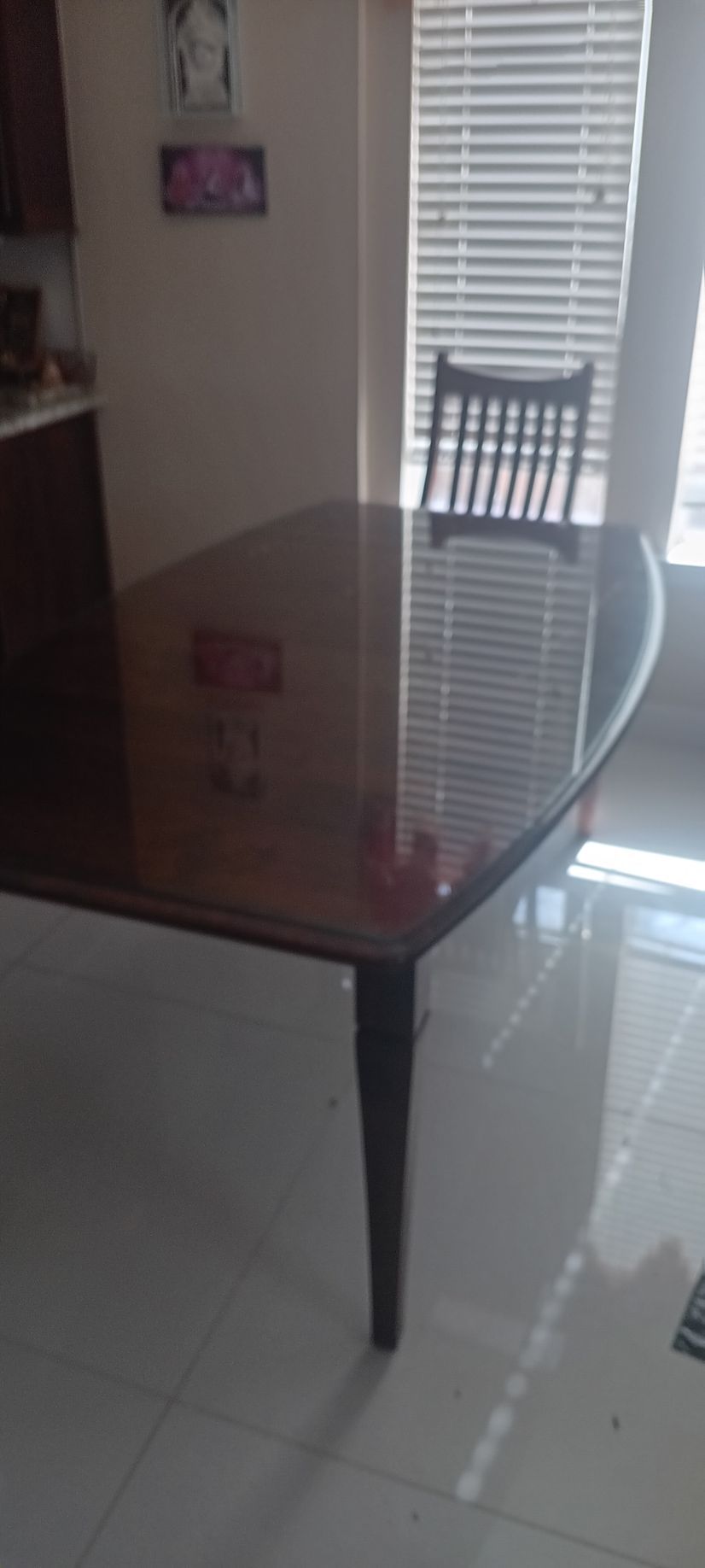A person sitting on a hardwood floor by a glass table, looking down at a small object in their hands.