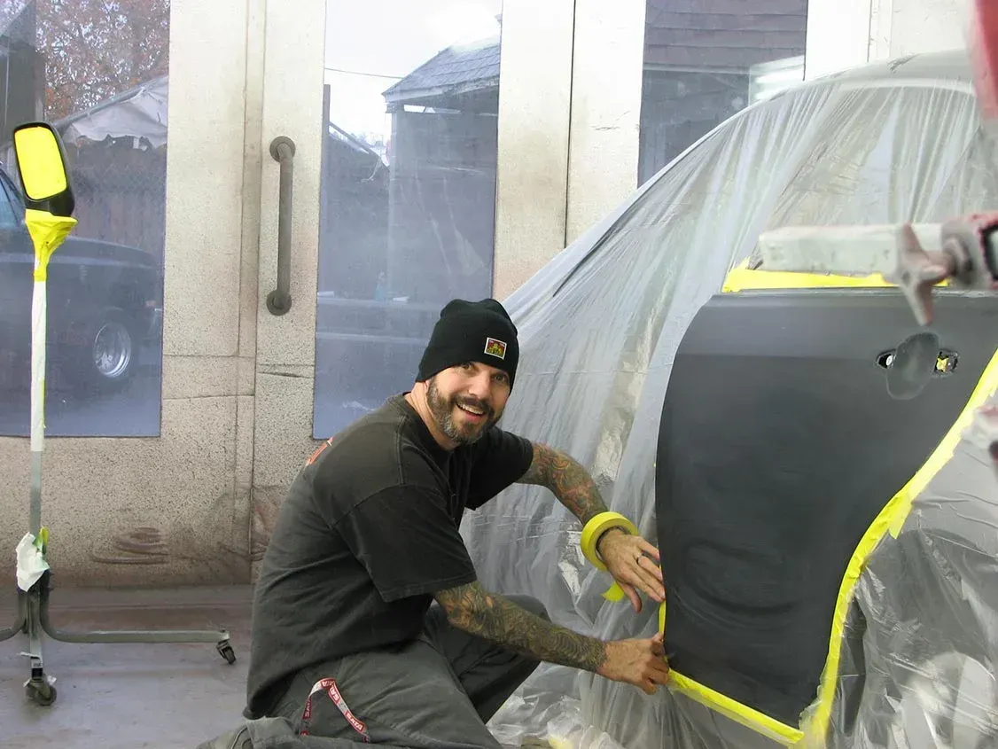 A Man Is Kneeling Down In Front Of A Car — Santa Rosa, CA — Precision Frame and Body Shop