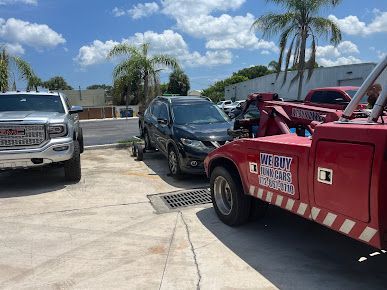 A white suv is being towed by a tow truck in a parking lot.