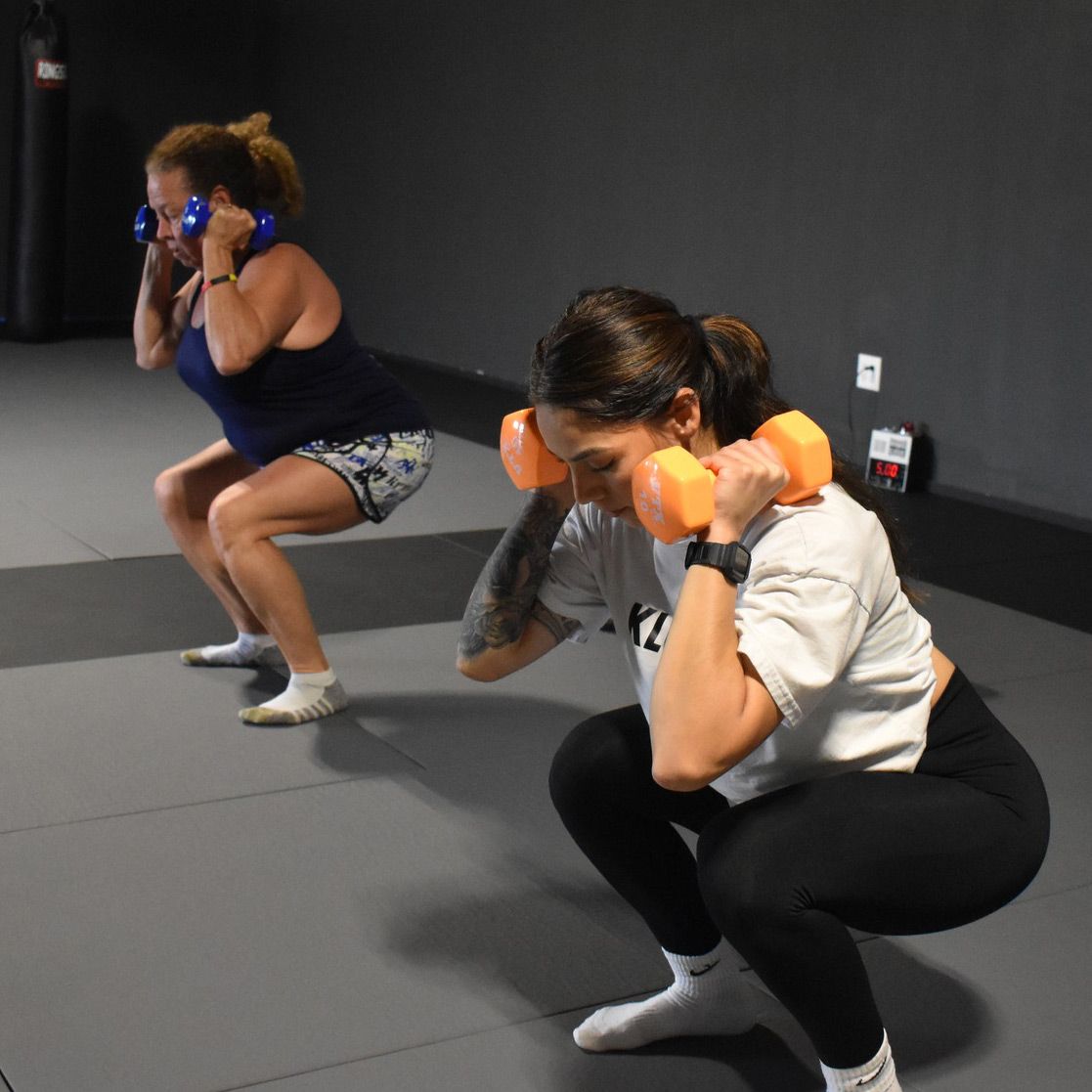 Two women squatting with dumbbells in their hands