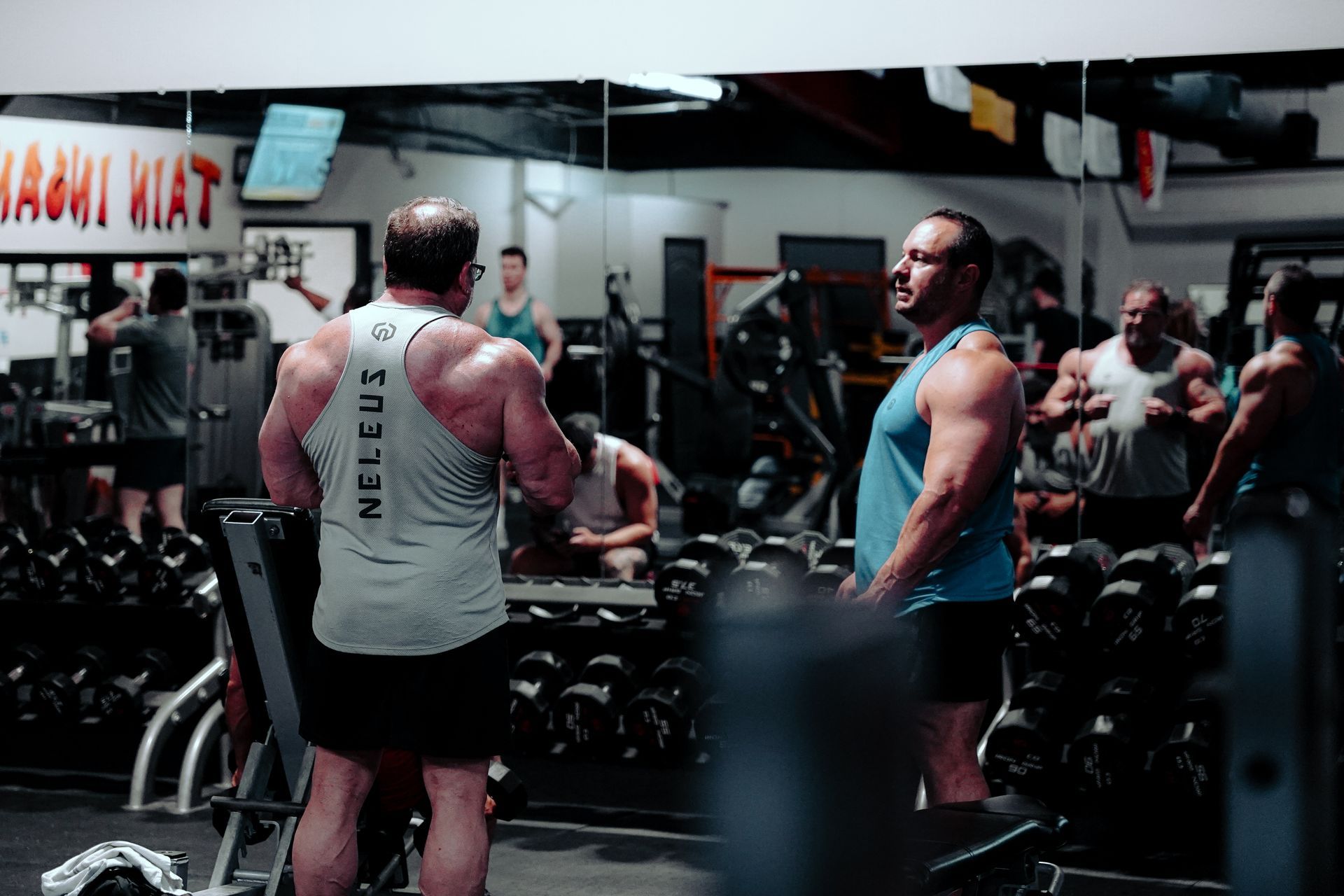A group of men are standing in a gym talking to each other.