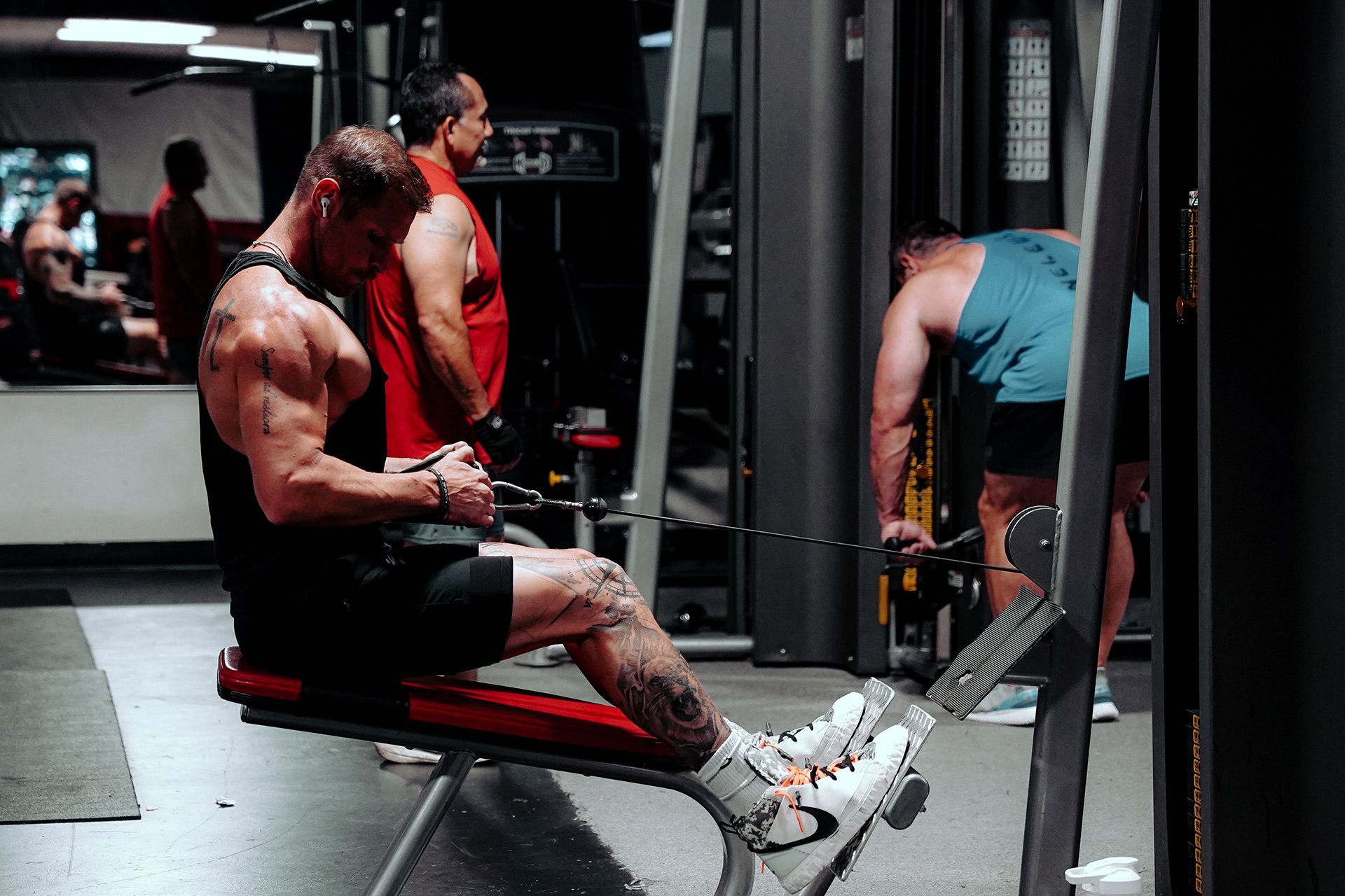 A man is sitting on a bench in a gym using a machine.