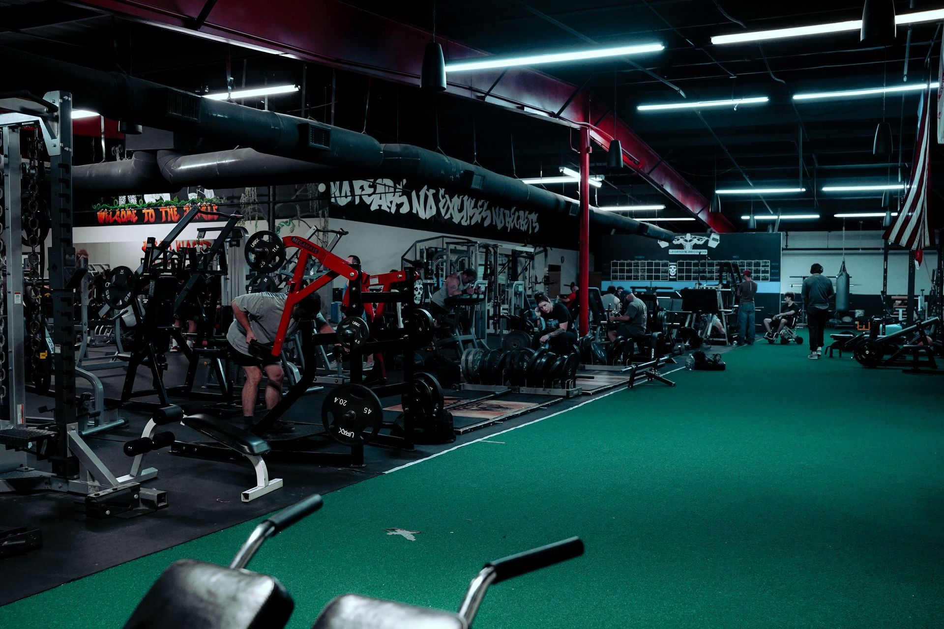 A gym filled with lots of exercise equipment and a green carpet.