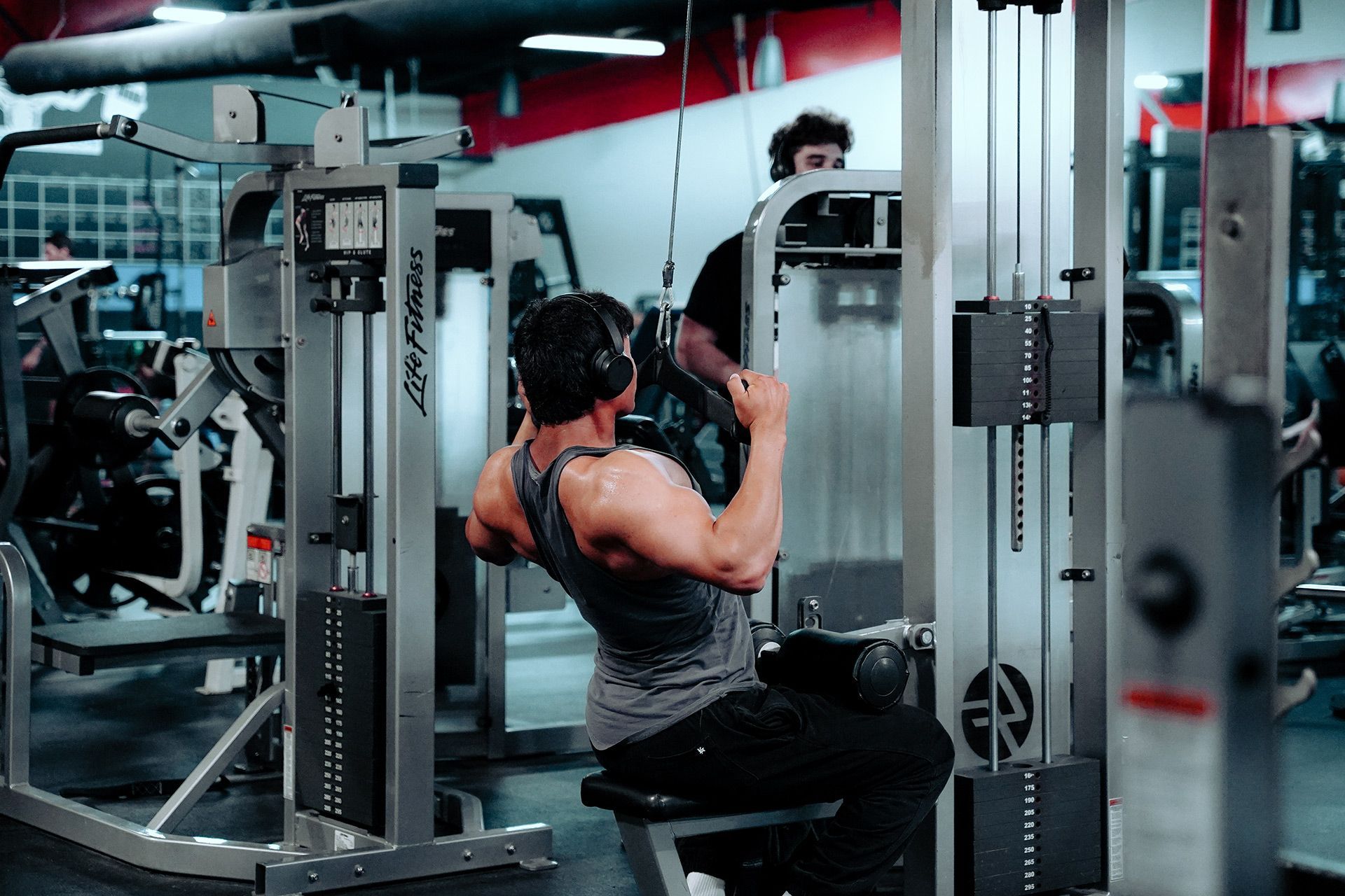 A man is sitting on a machine in a gym.