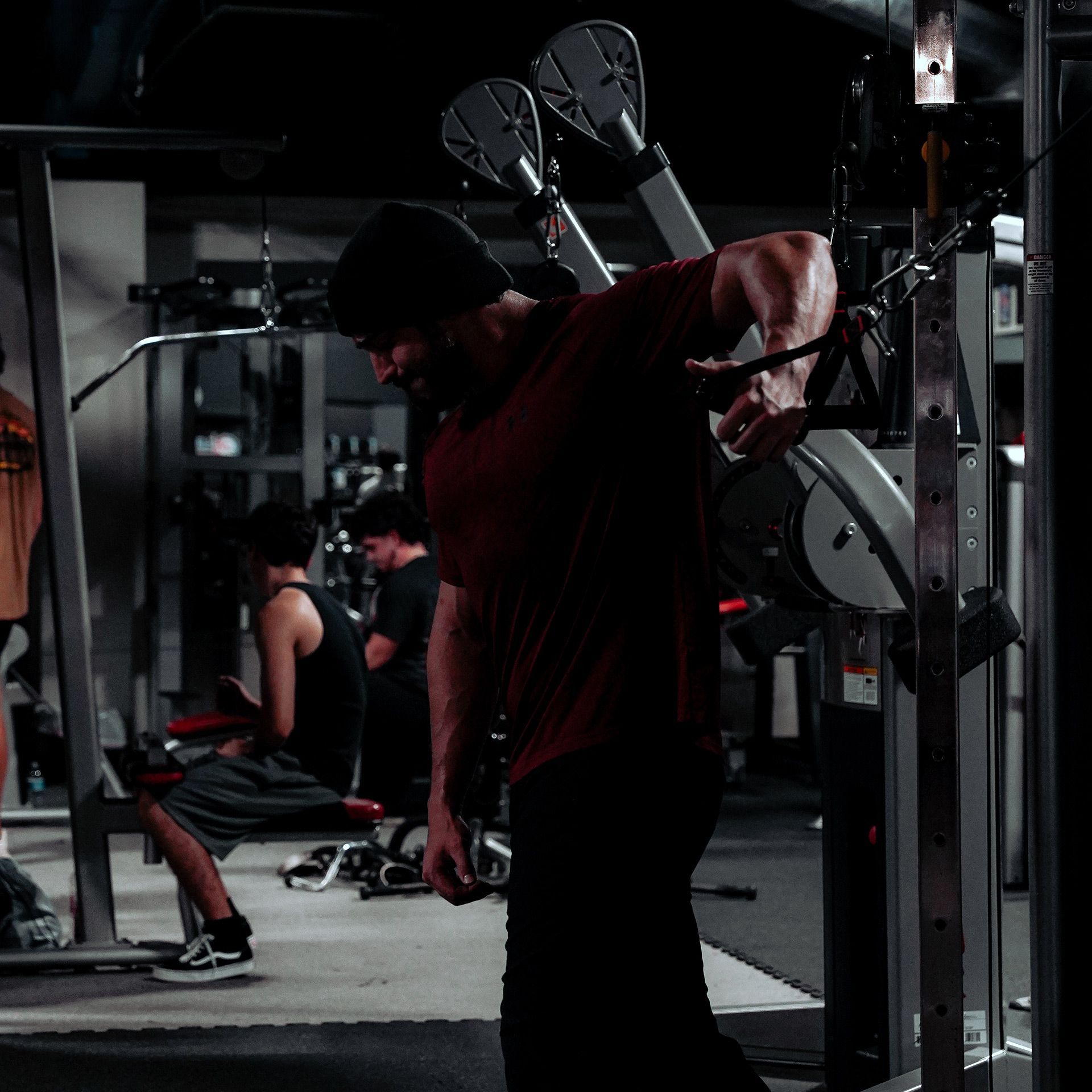 A man in a red shirt is using a machine in a gym