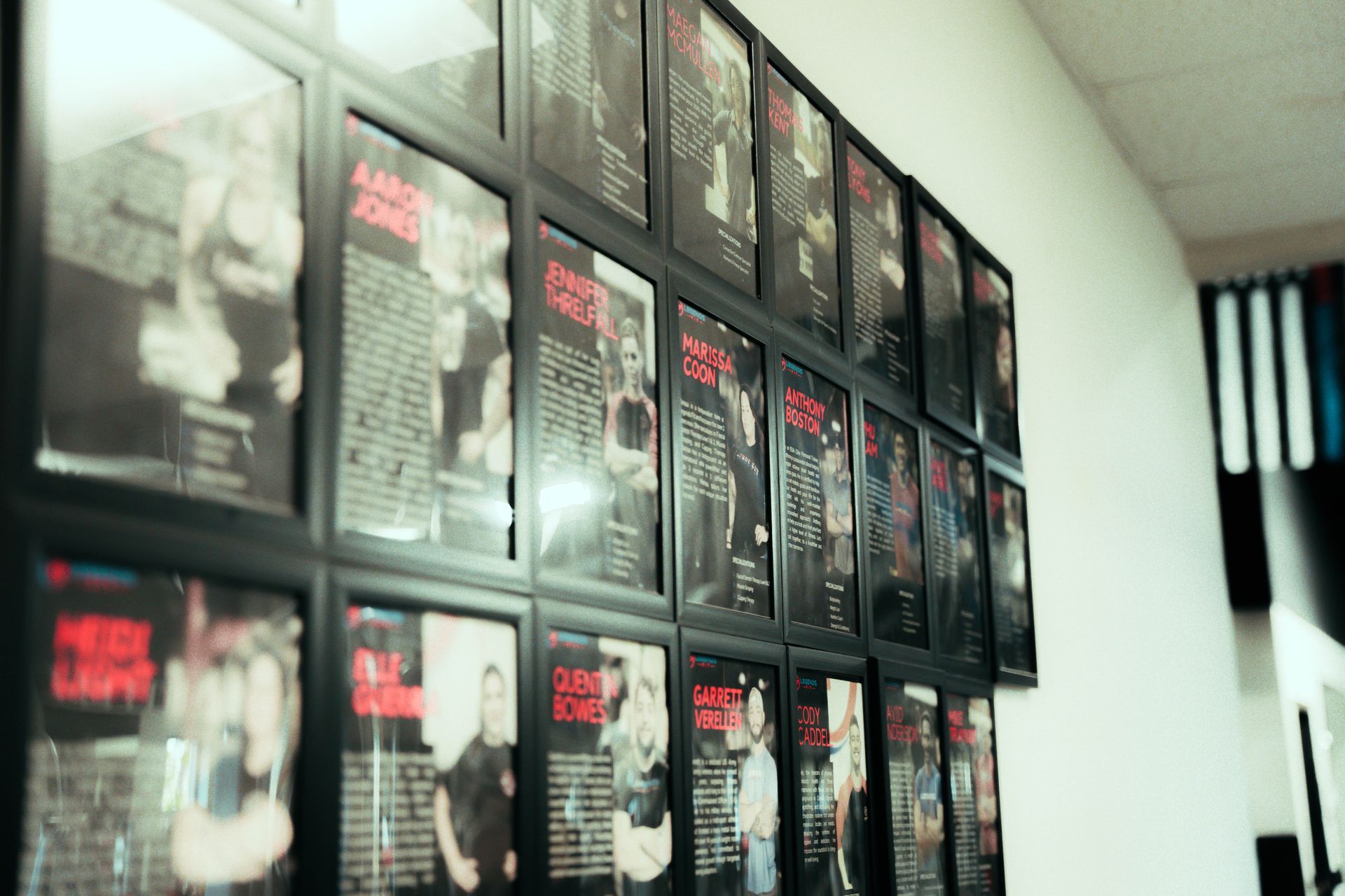 A wall filled with lots of framed pictures of people.