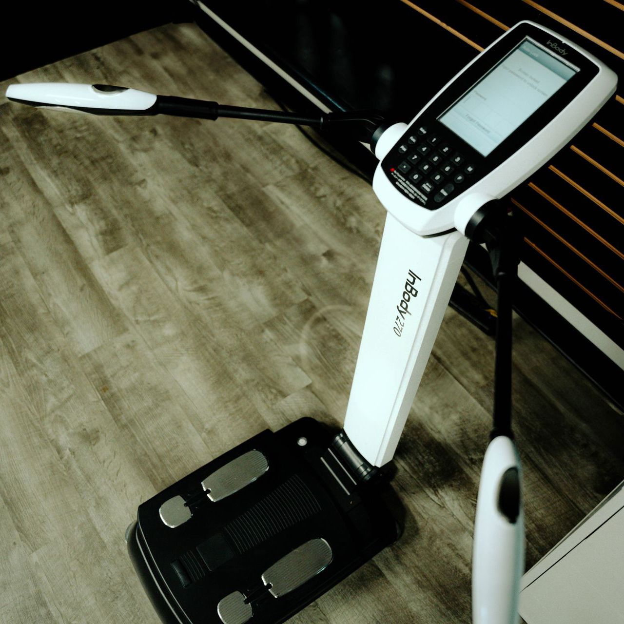 A white and black inbody machine is sitting on a wooden floor