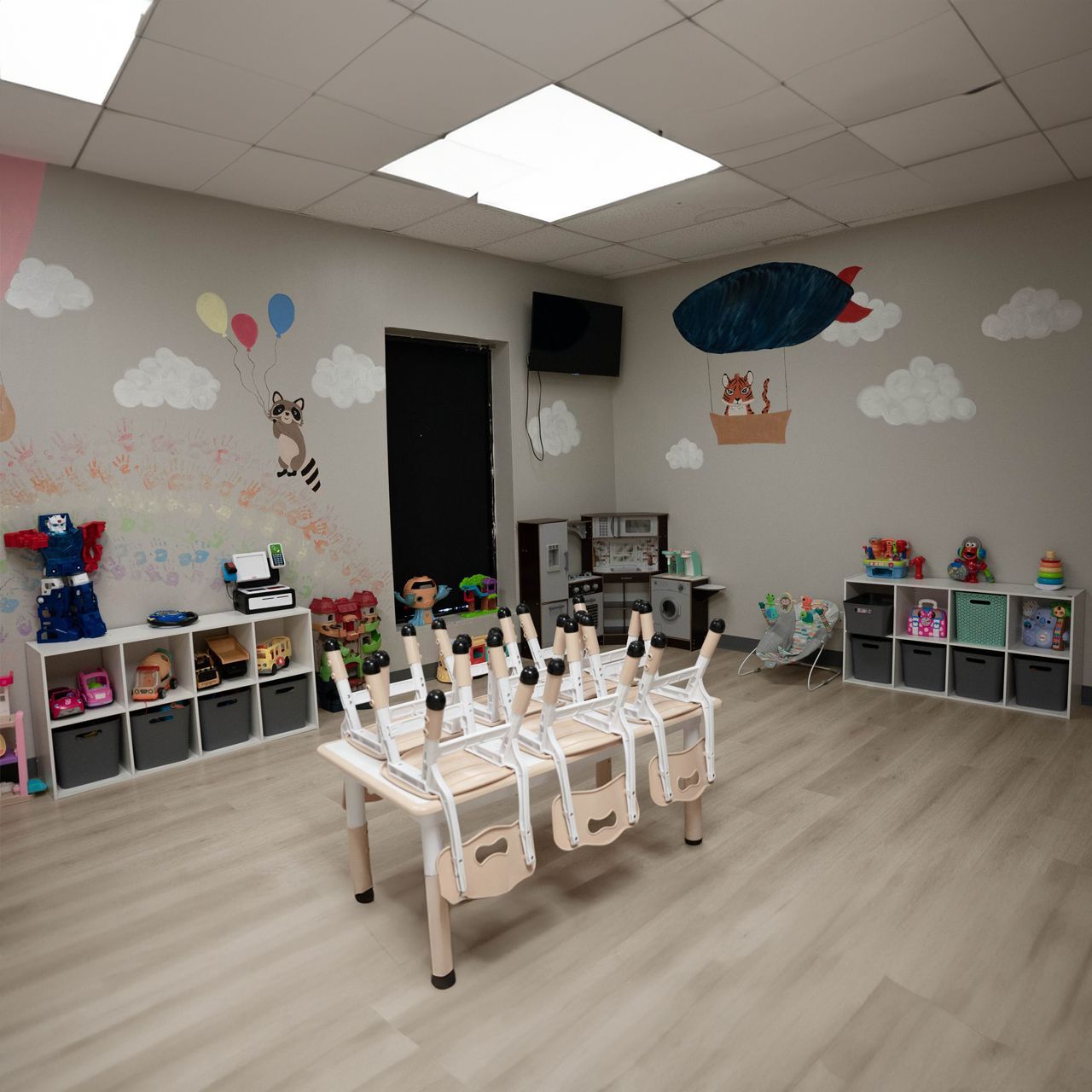 A room with a table and chairs and a hot air balloon on the wall