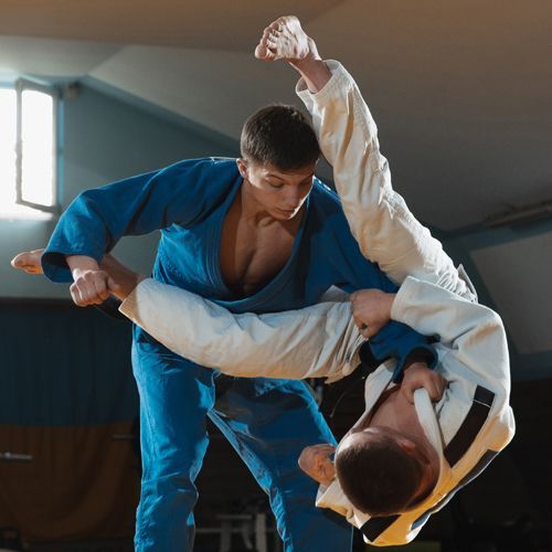 Two men are fighting judo in a gym.