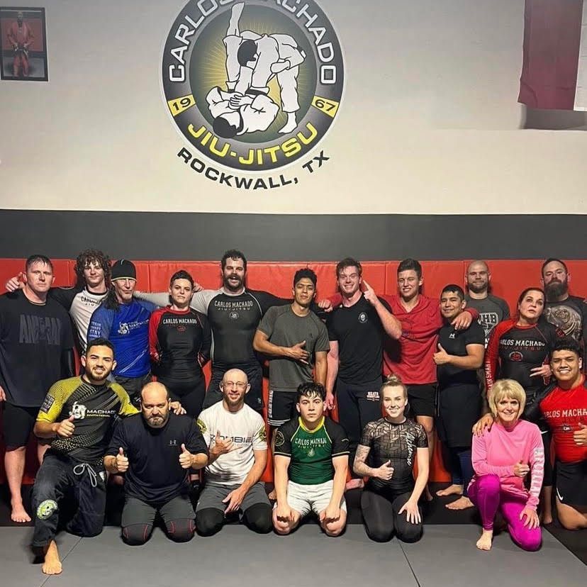 a group of people posing for a picture in front of a sign that says jiu-jitsu rockwall tx