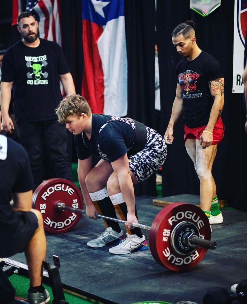 A man is lifting a barbell with the word rogue on it