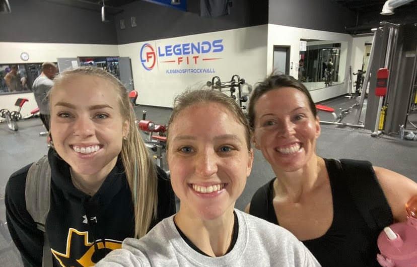 Three women are posing for a selfie in a gym.