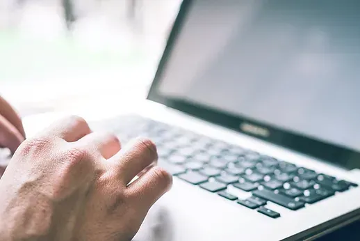 A person is typing on a laptop computer.